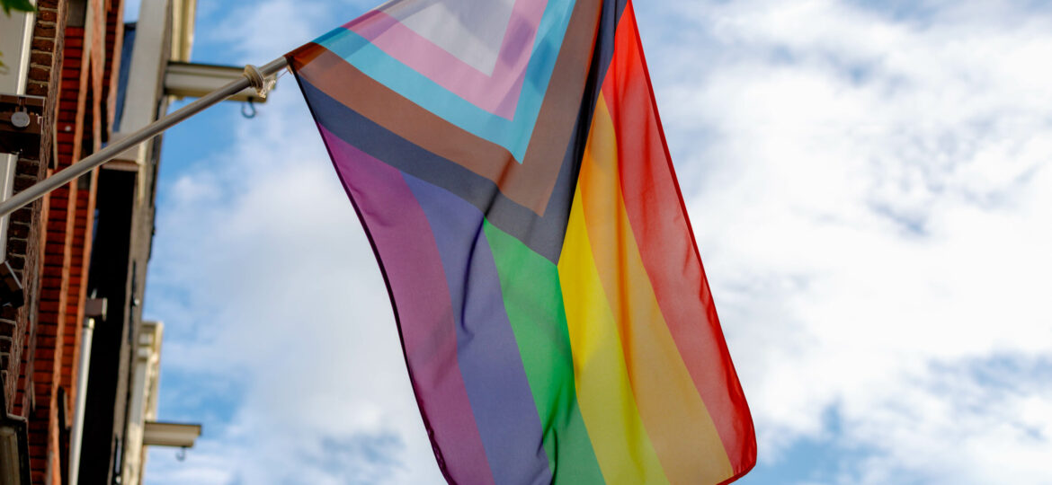 Progress pride flag (new design of rainbow flag) waving in the air with blue sky, Celebration of gay pride, The symbol of lesbian, gay, bisexual and transgender, LGBTQ community in Netherlands.